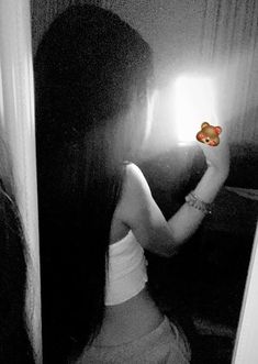 a woman holding a teddy bear up to her face while standing in front of a mirror