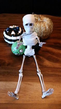 a skeleton is standing next to a green bowling ball on a wooden table with other decorations