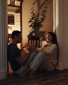 a man and woman sitting on the floor in front of a mirror looking at each other