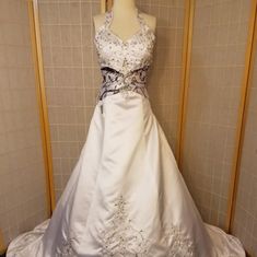 a wedding dress is displayed on a mannequin in front of a tiled wall