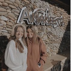 two young women standing in front of an advertisement for the angelfish resort, with their arms around each other