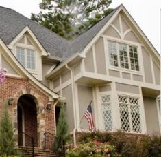 a house with flowers in front of it and an american flag hanging from the roof