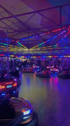 several bumper cars are lined up in a parking lot with colorful lights on the ceiling