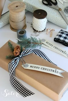 a christmas present wrapped in brown paper and tied with a black checkered ribbon on a white table