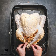 a person holding a whole turkey in their hands on a tray with other food items