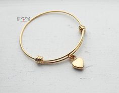 "This cremation urn bangle is made from gold plated stainless steel. Neither the bangle nor the heart shaped urn charm will rust or tarnish. The bangle is expandable, so it will fit most wrists. The gold plated heart shaped urn charm measures approximately 17mm (.7\"). The charm can be stamped with an initial upon request. The bracelet is approximately 60mm (fits 7\" to 9\") wrists. Please note when ordering that you will have to expand the bangle over your hand, so it does need to be larger tha Gold Heart-shaped Stainless Steel Bracelet, Minimalist Gold Bangle Heart Bracelet, Gold Minimalist Heart Bangle Bracelet, Gold Stainless Steel Heart Bracelet For Valentine's Day, Gold Stainless Steel Heart Bracelet For Anniversary, Gold Stainless Steel Bangle Charm Bracelet, Nickel-free Gold Heart Bracelet As Gift, Gold Heart Bracelet Nickel Free, Nickel-free Gold Heart Bracelet For Gift