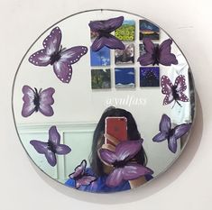 a woman taking a selfie in front of a mirror with purple butterflies on it