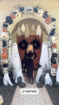 a woman standing in front of a door decorated with halloween decorations and fake ghost heads