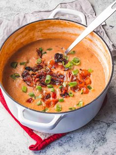 a pot filled with soup on top of a counter next to a red napkin and spoon