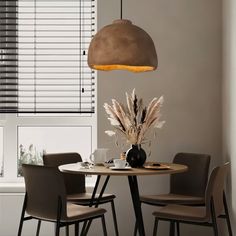 a dining table with four chairs and a vase on it in front of the window