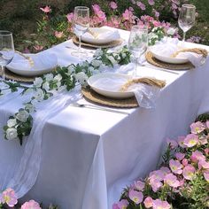 the table is set with white plates and flowers