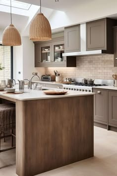 a large kitchen with an island in the middle and two pendant lights hanging from the ceiling