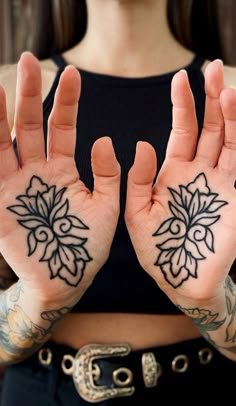 a woman with tattoos on her hands holding up two fingers and one hand in the shape of a flower