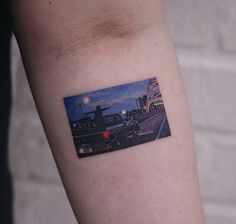 a person with a small tattoo on their arm that has a picture of a car in the background