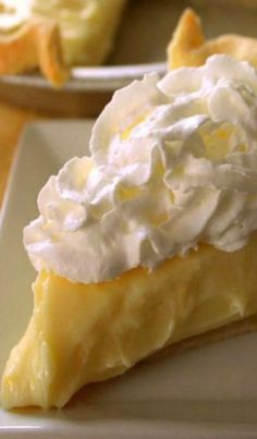 a slice of lemon meringue pie with whipped cream on top is sitting on a plate