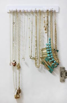 a bunch of necklaces are hanging on a white wall next to a key lock