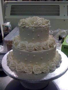 there is a three layer cake with white flowers on the top and bottom tiers