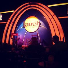 people are sitting on chairs in front of an orange and blue sign that says laugh