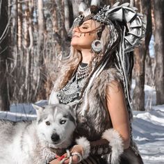 a woman in native garb holding a husky dog