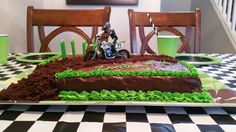 a cake that is sitting on top of a checkered tablecloth with green and black decorations