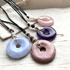 A choice of 30mm Pis tone donut pendants, that adjust to a choker or longer necklace. Wire wrapped in sterling silver spiral design. *AA Quality  gemstones. *Rose Quartz , Rhodonite, Blue Lace Agate and Amethyst. Purple and pink semi precious stone  pendants, *I wrapped them in 925 sterling silver wire spiral design. *This will stay beautiful forever. *I guarantee our wire wrap from unraveling.  *Each Natural crystal is attached to a strong dyrable cotton cord. ADJUSTABLE LENGTH Slide the knots Donut Crystal Necklace, Crystal Donut Necklace, Random Diys, Wire Wrapped Crystal Pendant, Crystal Wrap, Donut Pendant, Chakra Pendant, Rock Jewelry, Wire Wrapping Crystals