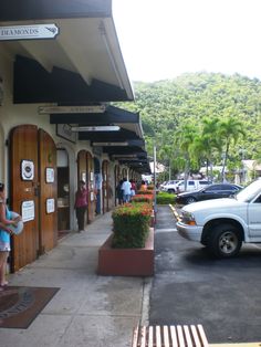 a woman standing in front of a building next to a parking lot filled with cars