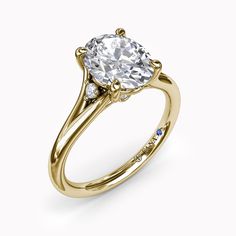 a yellow gold engagement ring with an oval cut diamond in the center and side stones