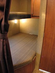 the inside of a camper with a bed and cupboards