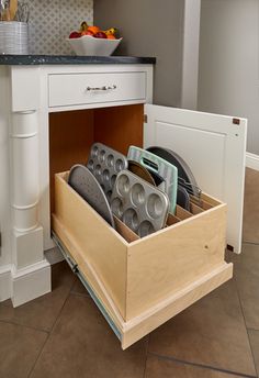 an open drawer in the middle of a kitchen with pots and pans inside it