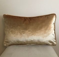 a gold pillow sitting on top of a white bed