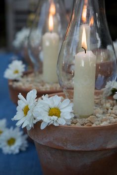 three vases filled with white flowers and lit candles