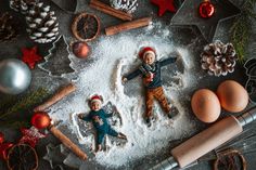 two children are laying in the snow next to christmas decorations and baking utensils