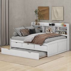 a white bed with drawers underneath it in a room