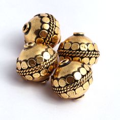 three gold toned beads are sitting on a white surface