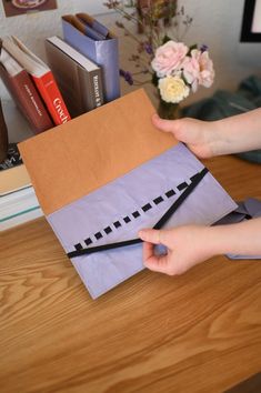 someone is making a paper bag that looks like an origami house on a table