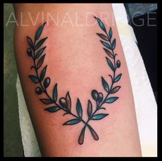 a black and white photo of a tattoo with an olive branch in the center on someone's arm