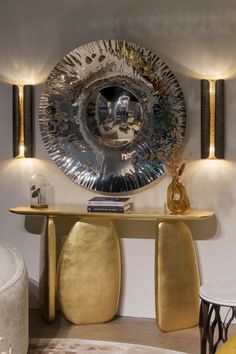 a table with two stools and a large metal plate on the wall behind it