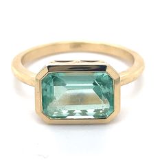 an emerald colored stone in a yellow gold ring