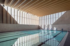 an indoor swimming pool in a building with large windows on the side and tiled floor