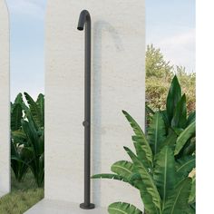 an outdoor shower in the middle of some grass and plants next to two white pillars