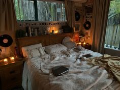 an unmade bed with candles and books on it