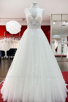 a white wedding dress on display at a bridal gown shop with red walls and black chairs