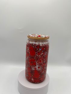 a glass jar filled with red liquid sitting on top of a white stand