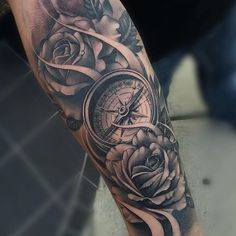 a black and white photo of a rose with a compass on it's arm