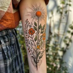 a woman's arm with flowers and sunbursts on it in front of her