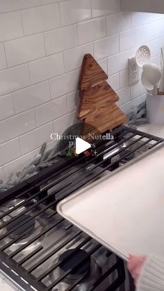 a stove top oven sitting inside of a kitchen next to a wooden christmas tree on the burner