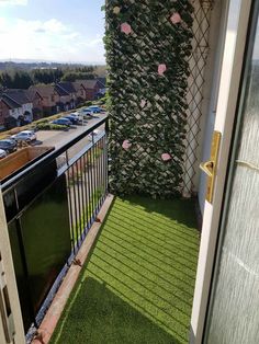 a balcony with artificial grass and flowers on the wall