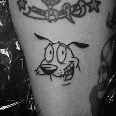 a black and white photo of a cartoon character tattoo on the leg, with skulls in the background