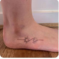 a small tattoo on the foot of a woman's foot, with an arrow and sun