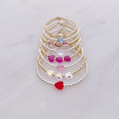 All of our bracelets are handmade in Hoboken, NJ, a little town which is near and dear to our hearts. This beautiful Swarovski heart bracelet is completely customizable - chose a single crystal heart or three. Also choose from 8 colors: red, fuchsia, rose, dusty lilac, mermaid, unicorn, clear, and silk. One inch of extra chain lets you adjust the bracelet to your preference. All items are hand-made in the USA in a smoke-free studio, and most importantly, they're made with OurWholeHeart❤︎ ------- Gold Heart-shaped Beaded Bracelet For Birthday, Dainty Beaded Bracelets With Heart Charm For Friendship, Heart Beads Bracelet Gift, Dainty Heart Charm Bracelet With Round Beads, Valentine's Day Beaded Bracelets With Heart Charm, Heart Charm Bracelet With Round Beads As Gift, Adjustable Heart-shaped Dainty Beaded Bracelets, Cute Silver Bracelets With Heart Beads, Dainty Adjustable Heart Shaped Beaded Bracelets